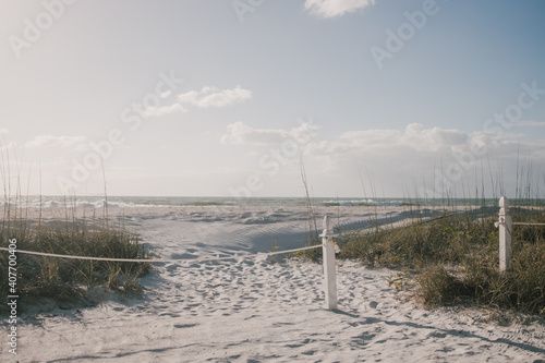 Cordoned-off pathway to the beach with the ocean  blue sky  and clouds in the background and seagrasses in the foreground 