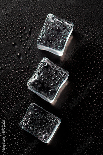 Three Ice cubes on black color texture. Concept art. Minimal surrealism. Flat lay with copy space. Soft focus. Vertical orientation.