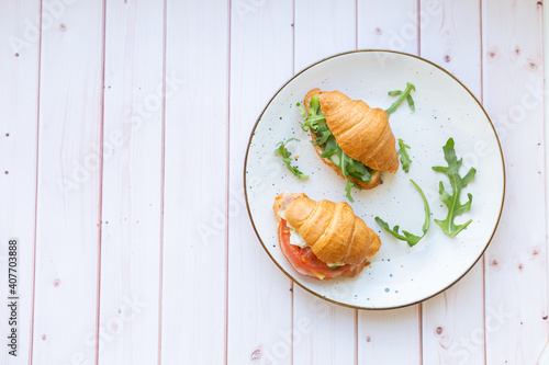 Two coissant with rocket salad and vegetables on a ceramic dish on a wooden table photo