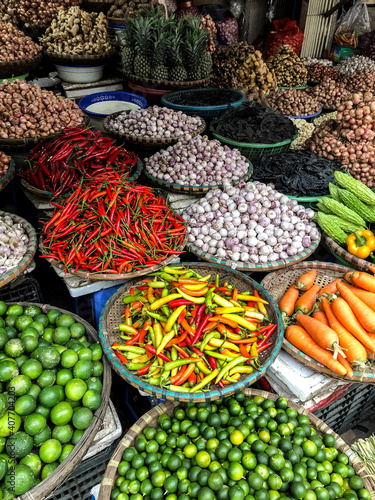 Fresh vegetables for sale at street food market in the old town of Hanoi, Vietnam. Garlic, Lemon, Ananas, Onions, Peper, Red chillies, carots
