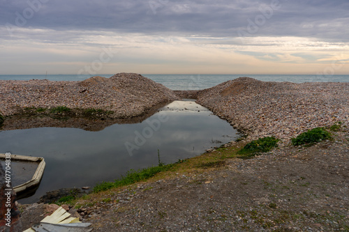 Arrival at the sea of the river La Marjal on the stony beach of Puzol photo