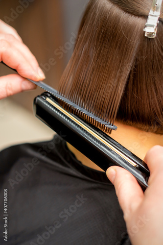 Valokuva Close up of the hairdresser straightening the short hair of a female client with