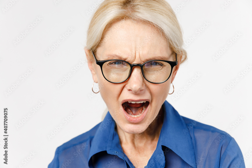 Close up blonde indignant angry displeased employee business woman 40s wearing blue classic shirt glasses formal clothes shouting screaming open mouth isolated on white background studio portrait