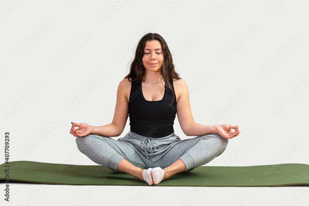 relaxed young woman meditating sitting in lotus pose on a green mat, isolated on white relaxed young woman meditating sitting in lotus pose on a green mat, isolated on white