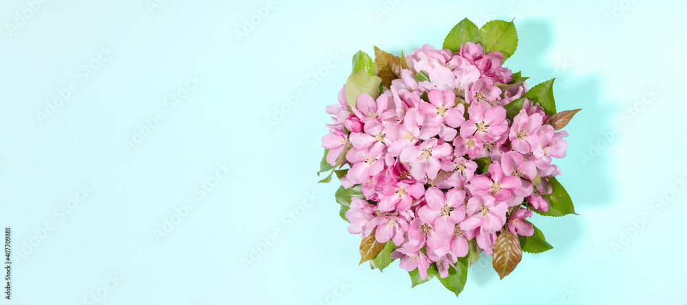 Banner with bouquet of blooming pink apple tree or sacura twigs on light blue. Holiday Valentine's Day, Mother's day, Birthday congratulations floral backdrop. Greeting card. Top view. Copy space.