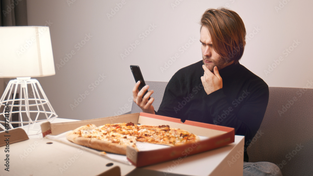 Young caucasian man taking a photo of pizza on his smartphone. . High quality photo Young caucasian man taking a photo of pizza on his smartphone. . High quality photo