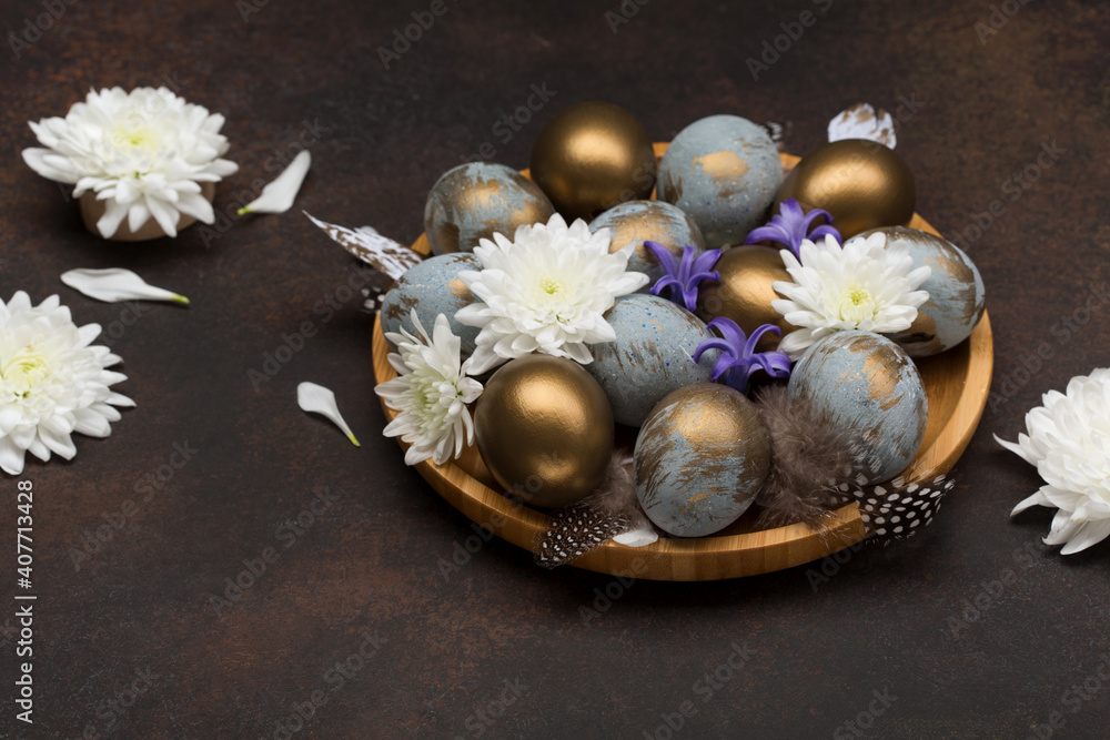 Easter Decoration with gray blue golden eggs, quail feathers, white flowers on dark wooden background. Selective focus, copy space.