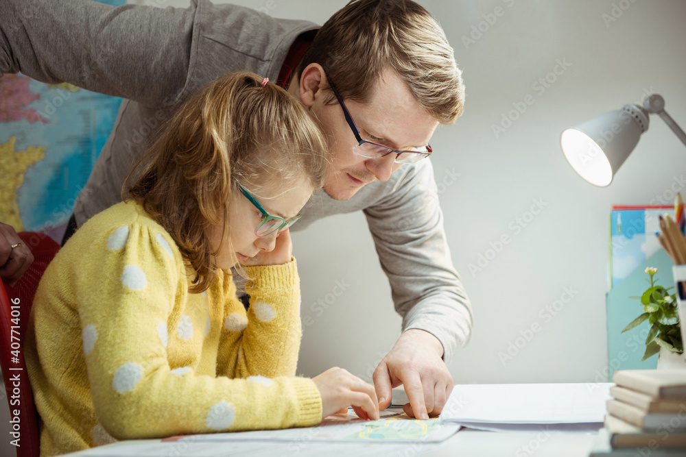Father teaching and helping daughter with homework during pandemic quarantine homeschooling Father teaching and helping daughter with homework during pandemic quarantine homeschooling