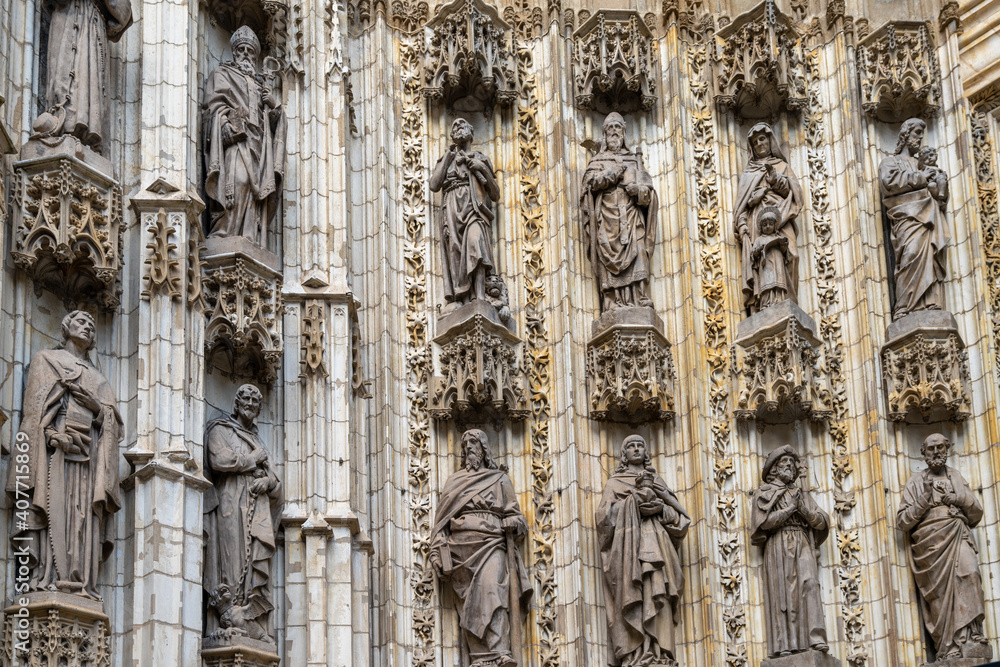 architectural detail of the door decorations and statues of the historic cathedral in Seville