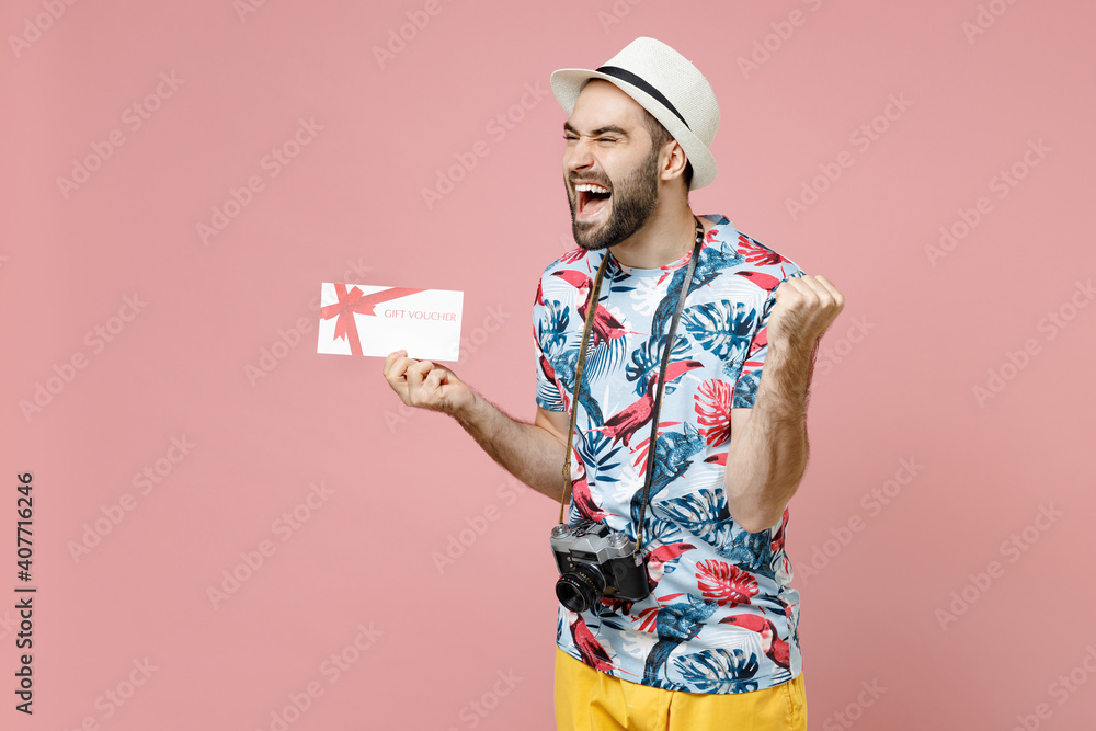 Joyful young traveler tourist man in summer basic clothes hat hold gift certificate doing winner gesture isolated on pink background studio. Passenger traveling on weekend. Air flight journey concept. Joyful young traveler tourist man in summer basic clothes hat hold gift certificate doing winner gesture isolated on pink background studio. Passenger traveling on weekend. Air flight journey concept.
