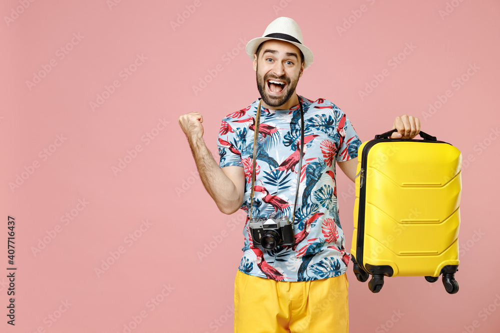 Joyful young traveler tourist man in summer clothes hat photo camera hold suitcase doing winner gesture isolated on pink background studio. Passenger traveling on weekends. Air flight journey concept. Joyful young traveler tourist man in summer clothes hat photo camera hold suitcase doing winner gesture isolated on pink background studio. Passenger traveling on weekends. Air flight journey concept.