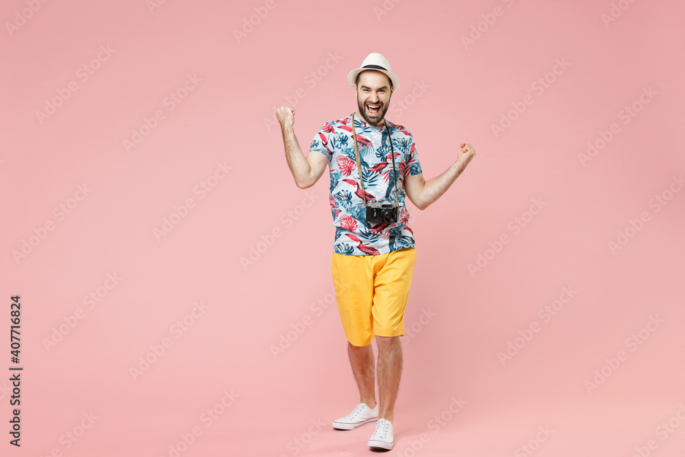 Full length of joyful young traveler tourist man in summer clothes hat doing winner gesture celebrating say yes isolated on pink background. Passenger traveling on weekend. Air flight journey concept. Full length of joyful young traveler tourist man in summer clothes hat doing winner gesture celebrating say yes isolated on pink background. Passenger traveling on weekend. Air flight journey concept.