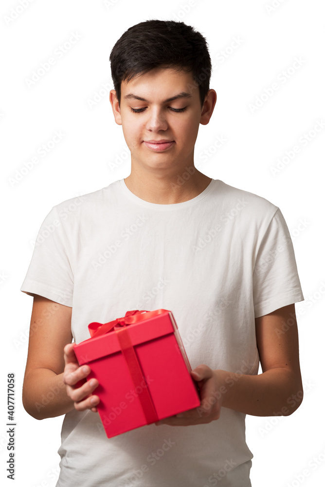 Handsome caucasian teen guy holding red gift box with both hands isolated on white background. Concept of preparation to holidays. Focus on face.