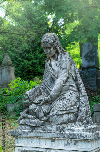 Lviv, Ukraine - July 12, 2019: Ancient gothic Lychakiv cemetery in Lvov, Ukraine. Ancient stone crypts, tombs and gravestones against the backdrop of overgrown green trees and herbs. Famous landmark