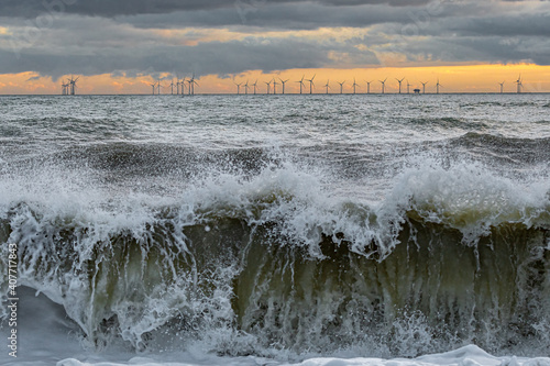 Waves crashing on windy day near offshore wind farm