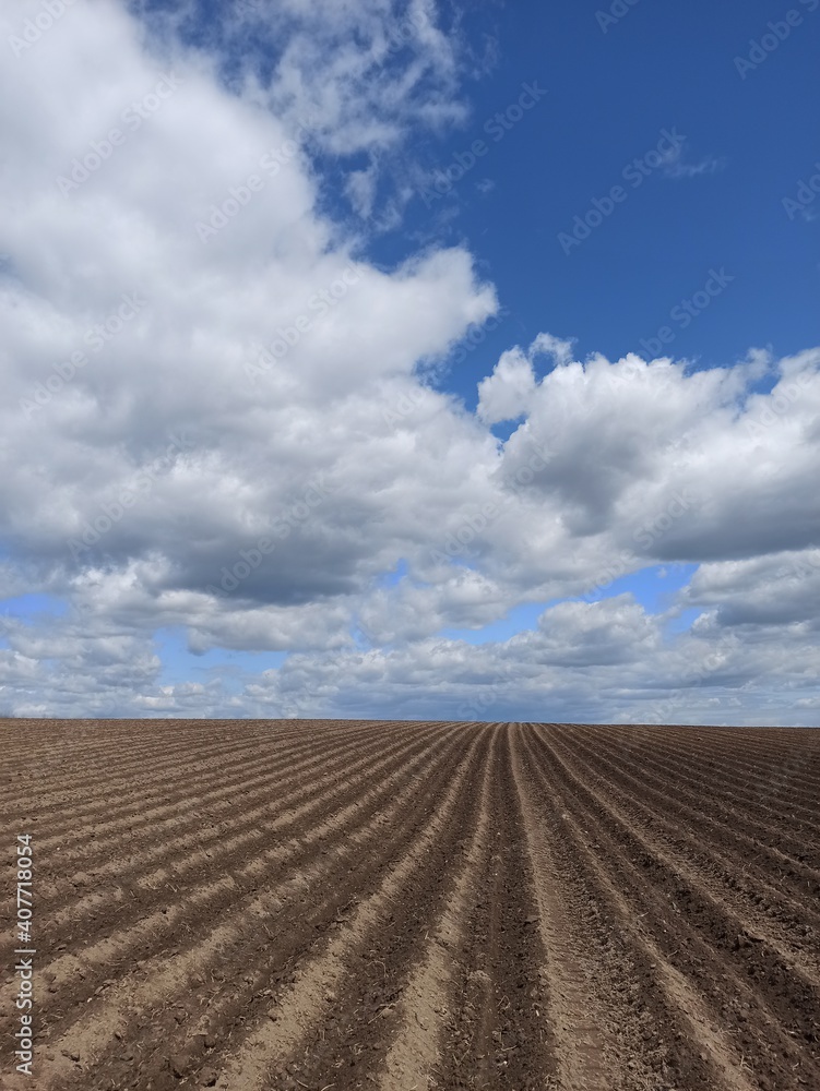 Beautiful plowed field and blue sky with clouds, nature background, landscape. Agriculture topic Beautiful plowed field and blue sky with clouds, nature background, landscape. Agriculture topic