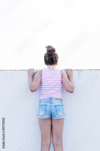 young girl with her back against a wall facing the other way