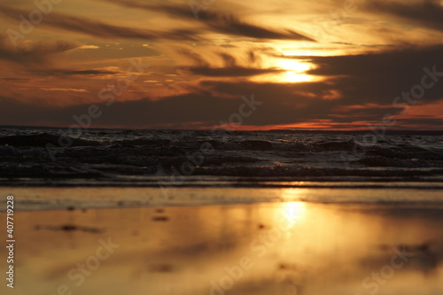 Calm sea at sunset. The water has no big waves and the sky is coloured in orange and yellow. The water is dark. The image is suitable for wallpapers. © Viktor Yurkin