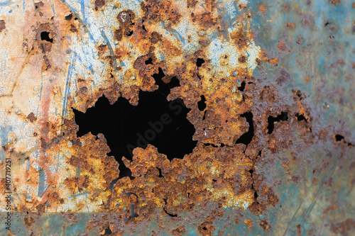 Old steel tank is holes from rust close up.
