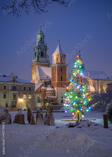 Illuminated Christmas tree on snow at night, Wawel cathedral and castle, Krakow, Poland