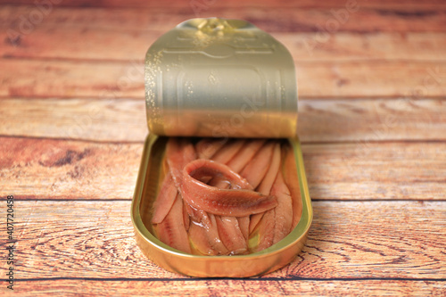 Open can of Cantabrian anchovies (Santoña anchovies) on wooden table with blur and blank space photo