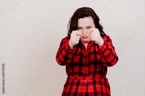 Attractive woman in red dress shows indecent gestures on a white background. photo