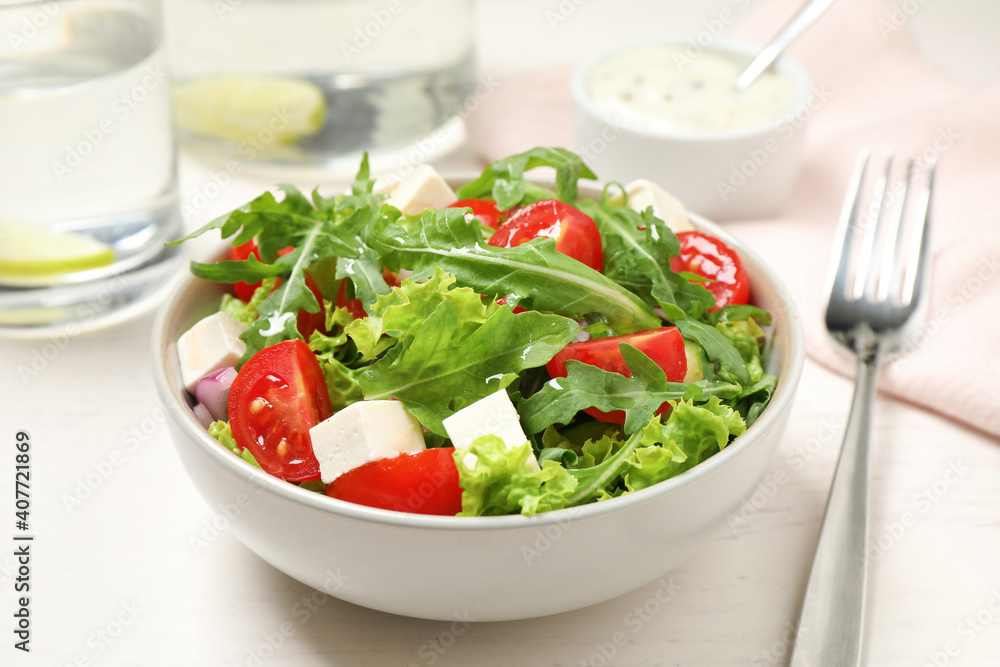Delicious salad with arugula and vegetables on white table, closeup Delicious salad with arugula and vegetables on white table, closeup