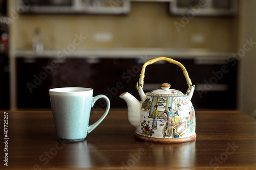 A table on which there is a mug of tea and a kettle.
