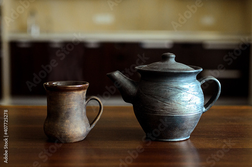 A table on which there is a mug of tea and a kettle.