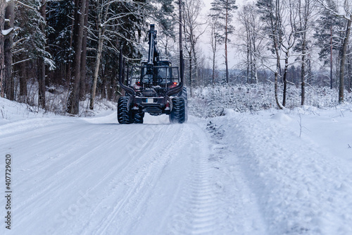 Logging machine driving on snowy winter forest road. Forestry, forest management. © RasaBasa