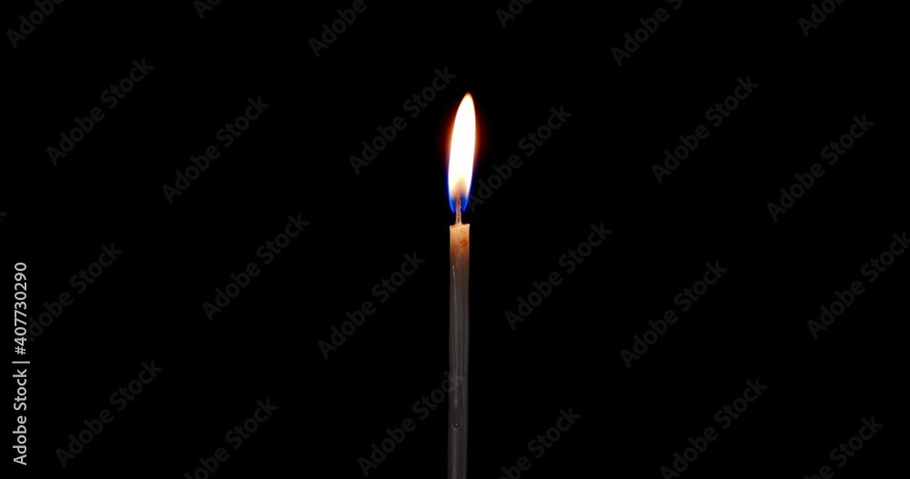 A single white candle burning. Isolated candle burning with dark background. White paraffin candle with yellow shades burns on a black background. Perfect for the layer with different blending modes.
