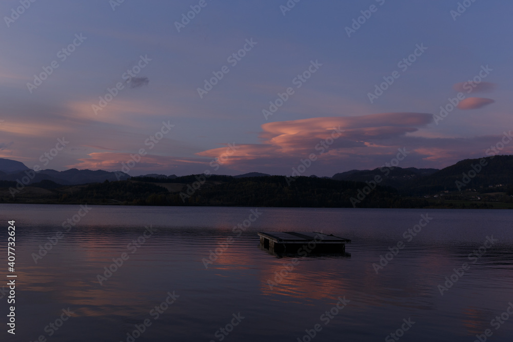 Velenia Lake in Slovenia at sunset with a chimney smoking