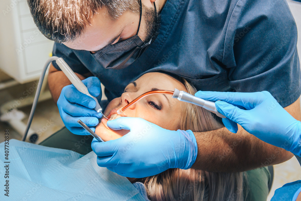 A girl at the reception of a male dentist in a dental chair, with her mouth open during a dental cleaning procedure. A girl at the reception of a male dentist in a dental chair, with her mouth open during a dental cleaning procedure.