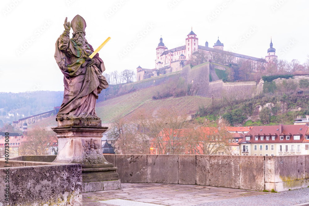 Obraz premium Statue of Saint Kilian on Old Main Bridge, Alte Mainbrucke, with Fortress Marienberg in the background, Wurzburg, Bavaria, Germany