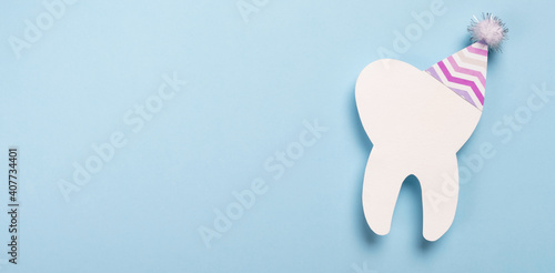 Canvas Print Decorative model tooth in a festive cap on light blue background