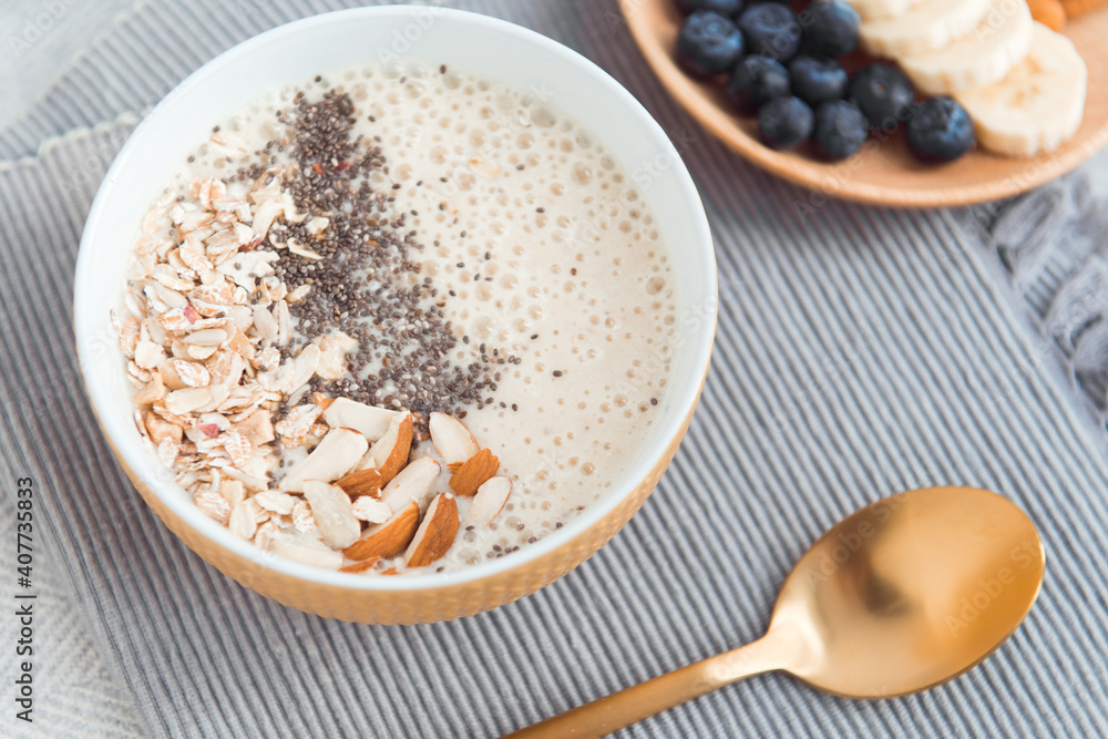 Healthy breakfast fruit smoothie bowl topped with almond, granola and chia seeds, snack banana and blueberry Healthy breakfast fruit smoothie bowl topped with almond, granola and chia seeds, snack banana and blueberry