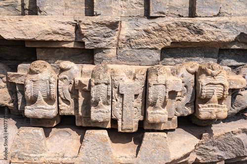 Lakkundi, Karnataka, India - November 6, 2013: Brahma Jinalaya temple. Closeup of brown stone sculpted detail of sanctum wall under sunshine. photo