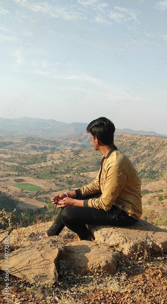 An Indian boy sitting on the top of a mountain An Indian boy sitting on the top of a mountain
