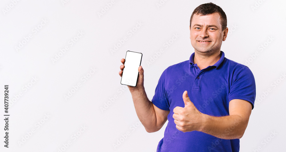 Banner. Deaf senior man shows thumb up while holding a mobile phone, white screen to the camera. White background and blank advertising space. Banner. Deaf senior man shows thumb up while holding a mobile phone, white screen to the camera. White background and blank advertising space.