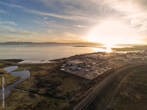 Galway bay and port commercial buildings at sunset, railroad to town. Aerial drone view.