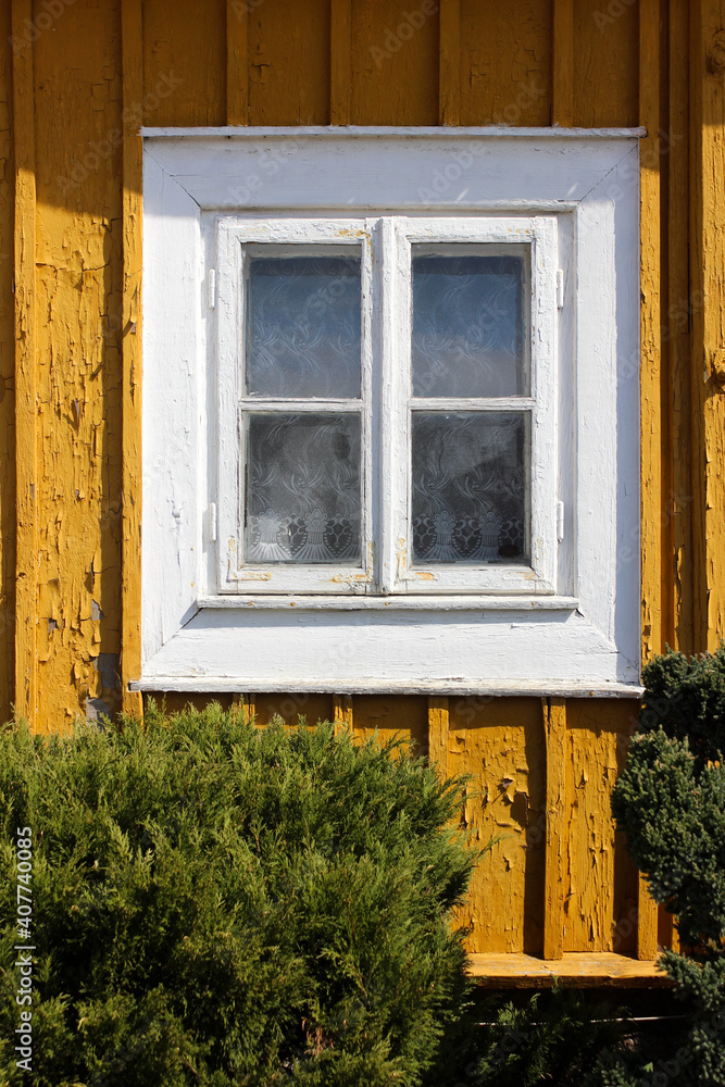 Old white wooden window and yellow facade of an old house. Old white wooden window and yellow facade of an old house.