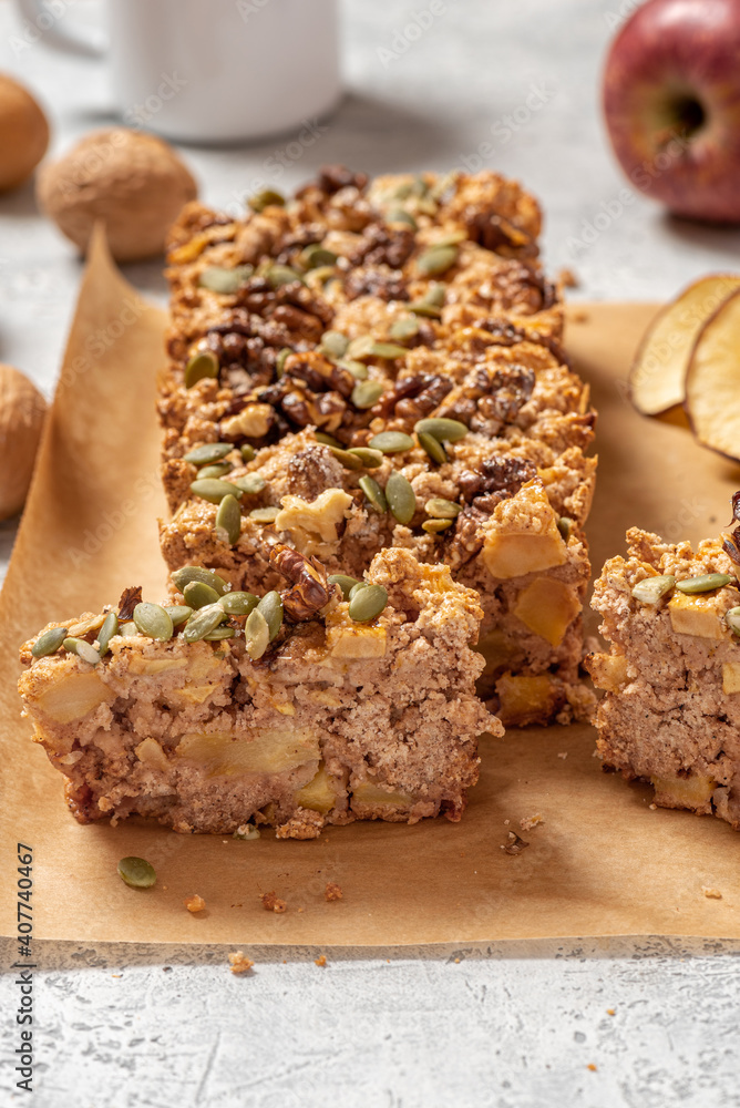 Gluten-free apple cake with walnuts, pumpkin seeds, cinnamon, and nutmeg. Freshly baked apple cake on baking paper close-up. Sweet vegetarian food, vegan dessert. Gluten-free apple cake with walnuts, pumpkin seeds, cinnamon, and nutmeg. Freshly baked apple cake on baking paper close-up. Sweet vegetarian food, vegan dessert.