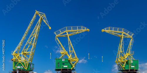 three colorful industrial cranes on a blue sky background