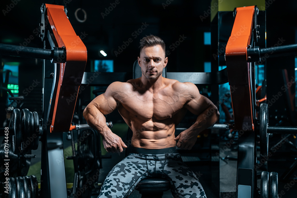 Naklejka premium young athletic sportsman bodybuilder with muscle perfect body has workout in gym