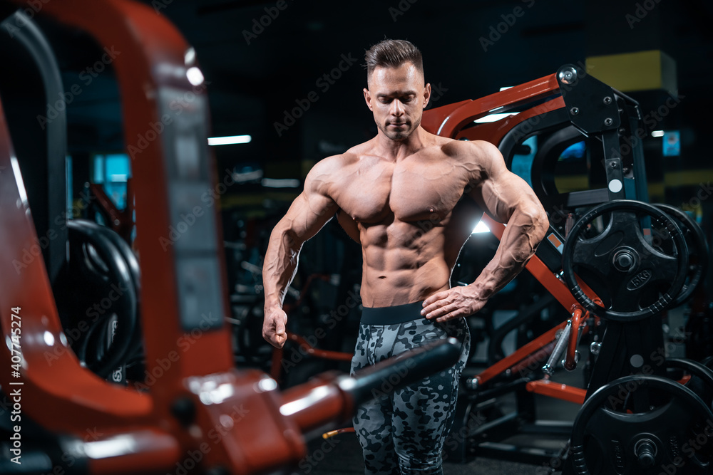 Naklejka premium young athletic sportsman bodybuilder with muscle perfect body posing in gym