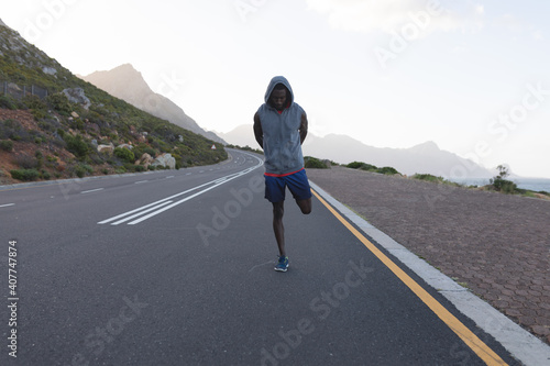 Fit african american man in sportswear stretching on a coastal road