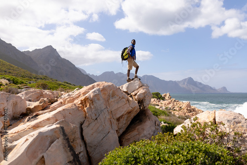 Fototapeta Fit afrcan american man wearing backpack hiking on the coast