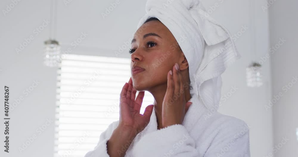 African american woman in bathrobe touching her face in the bathroom African american woman in bathrobe touching her face in the bathroom