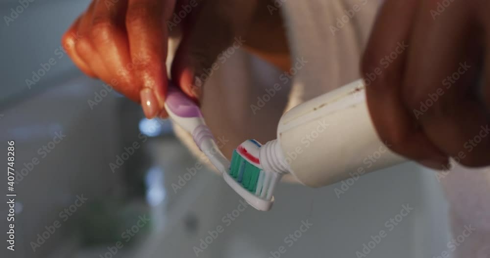 Close up of african american woman putting toothpaste on her brush in the bathroom Close up of african american woman putting toothpaste on her brush in the bathroom