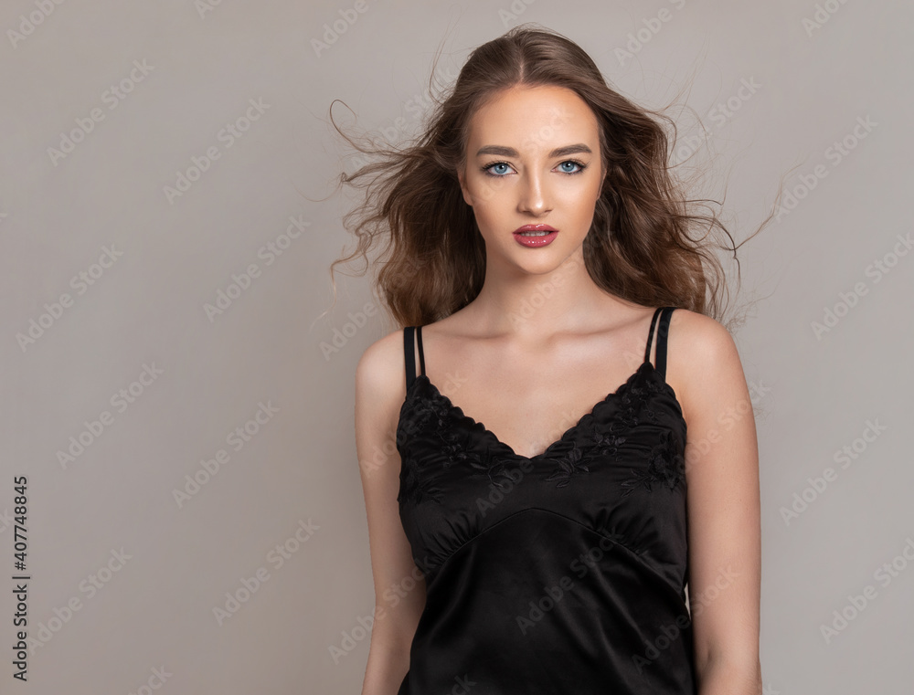 Beautiful young woman with long and healthy wavy hair posing in dress showing healthy figure and wearing wrist watch Beautiful young woman with long and healthy wavy hair posing in dress showing healthy figure and wearing wrist watch